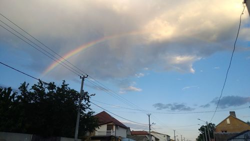 Low angle view of rainbow over buildings against sky
