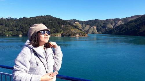 Smiling woman standing against river