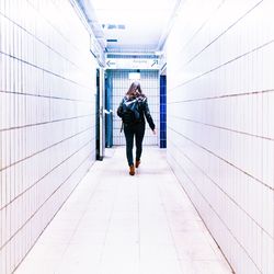 Full length rear view of woman standing on footbridge