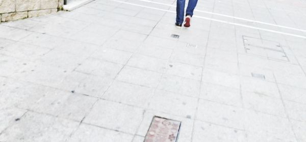 Low section of man walking on tiled floor