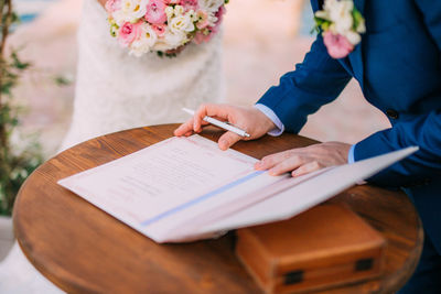 Midsection of man signing agreement during wedding