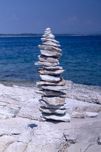 Stack of pebbles on beach against sky