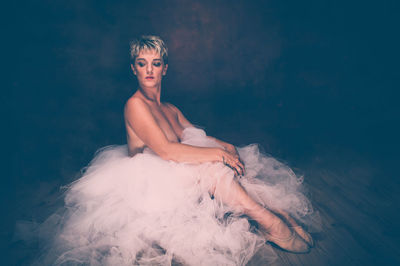 Semi-naked woman wearing tulle tutu against black background