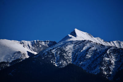 Scenic view of snowcapped mountains against clear blue sky