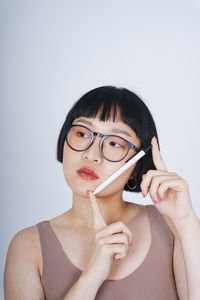 Young woman holding pen against white background