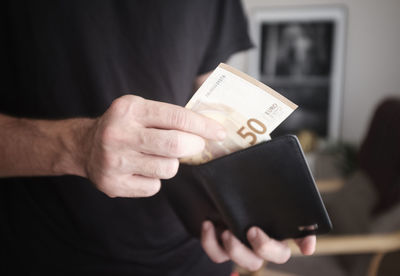 Midsection of man removing paper currency from wallet