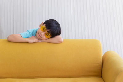 Portrait of smiling boy wearing sunglasses by sofa