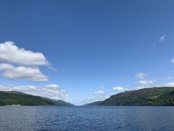 Scenic view of sea by mountains against sky