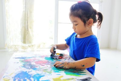 Cute girl painting on paper at home