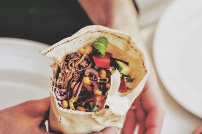 Cropped image of hand holding wrap sandwich