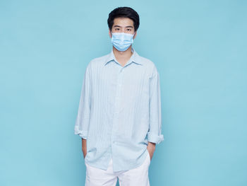 Portrait of young man standing against blue background