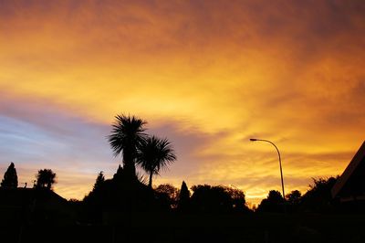 Low angle view of silhouette palm trees against orange sky