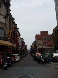 Cars on street in city against sky