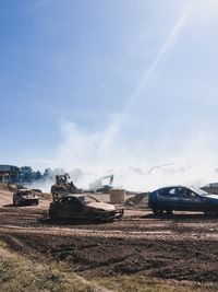 Cars on road amidst field against sky