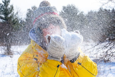 Close-up of senior woman blowing ice outdoors