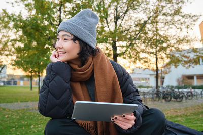 Young woman using mobile phone while sitting on field