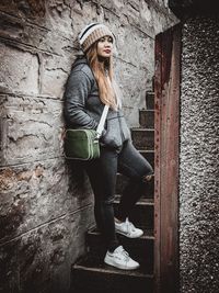 Portrait of woman standing against wall