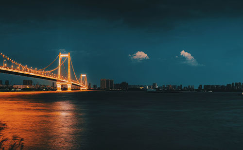 View of suspension bridge over river at night