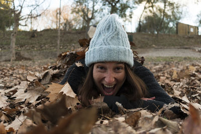 Portrait of excited woman lying on autumn leaves