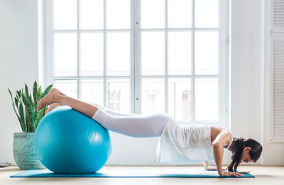 Full length of young woman exercising at home