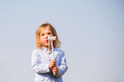 Portrait of young woman drinking water against clear sky