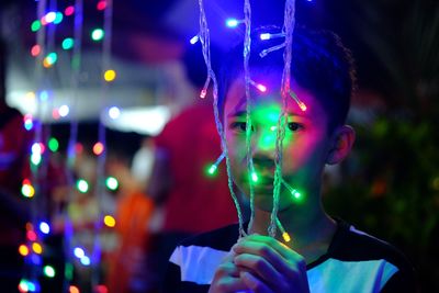Portrait of boy holding multi colored lights over face