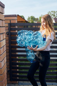 Young woman throwing out empty used plastic water bottles into trash bin. collecting plastic waste