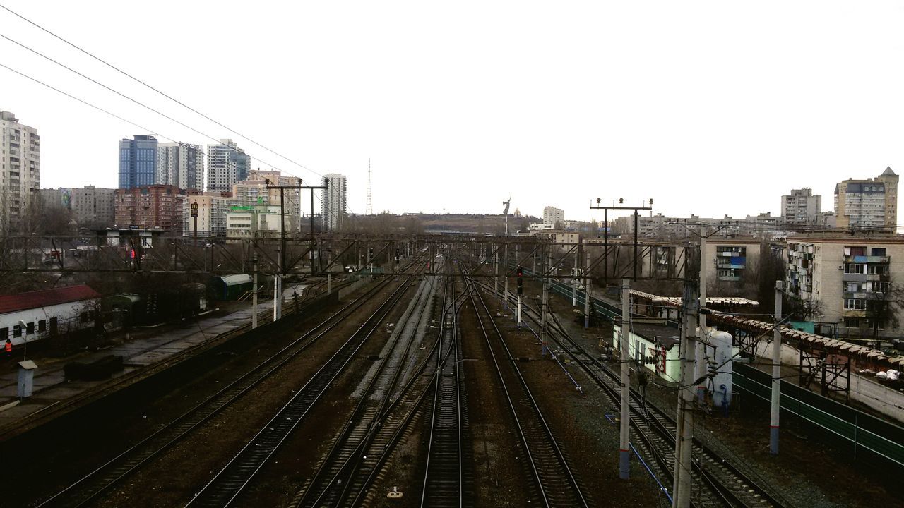 railroad track, transportation, rail transportation, high angle view, built structure, building exterior, architecture, outdoors, sky, city, public transportation, mode of transport, clear sky, day, no people, tree