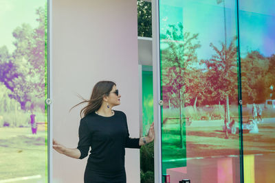 Mid adult woman wearing sunglasses standing at doorway