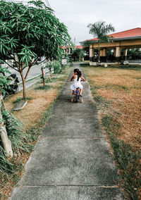 Rear view of man riding bicycle on footpath