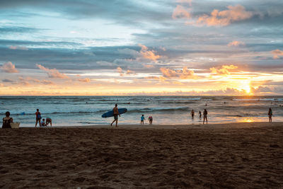 Silhouette people on beach against sky during sunset