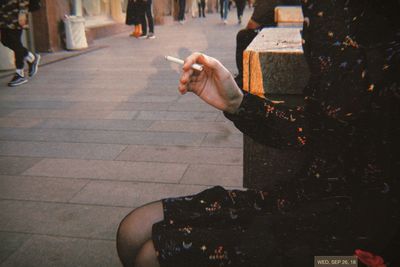 Man holding cigarette on street in city