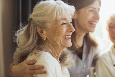 Happy elderly woman by female caregiver at nursing home