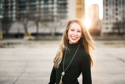 Portrait of smiling young woman against river in city