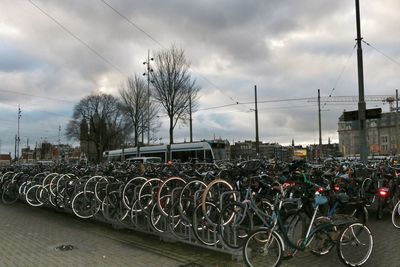 Bicycles parked in row against cloudy sky