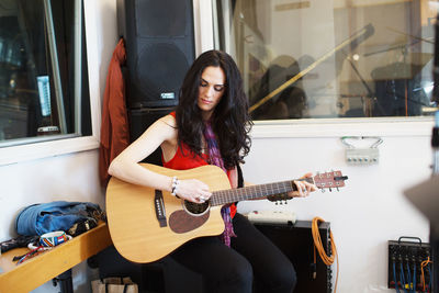 Young woman playing acoustic guitar at a recording studio