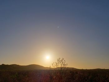 Scenic view of land against clear sky during sunset