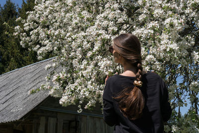 Full length of woman standing by flowering tree