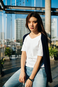 Portrait of woman standing against railing in city