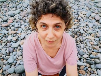High angle portrait of mature woman sitting on pebbles