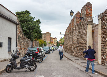 Rear view of people walking on street amidst buildings in city