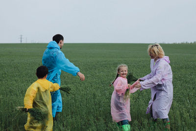 Happy family playing on field against sky