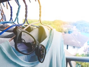 Close-up of sunglasses on coathanger against sky