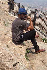 Young man sitting on fence