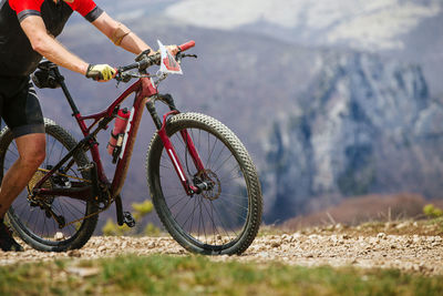 Low section of man riding bicycle on field