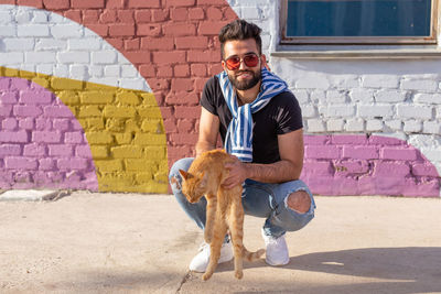 Young man with dog standing against wall