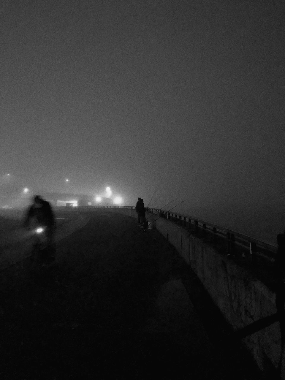 PEOPLE WALKING ON ILLUMINATED BRIDGE AT NIGHT