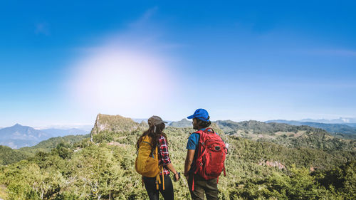 Rear view of woman standing on mountain against clear blue sky