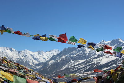 Low angle view of colorful prayer flags at himalayas against clear blue sky