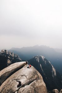 People standing on cliff against clear sky